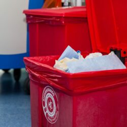 Biological risk waste disposed of in the red trash bag at a operating room in a hospital. Sign showing the biological hazard symbol and the types of waste considered in this category in spanish and english