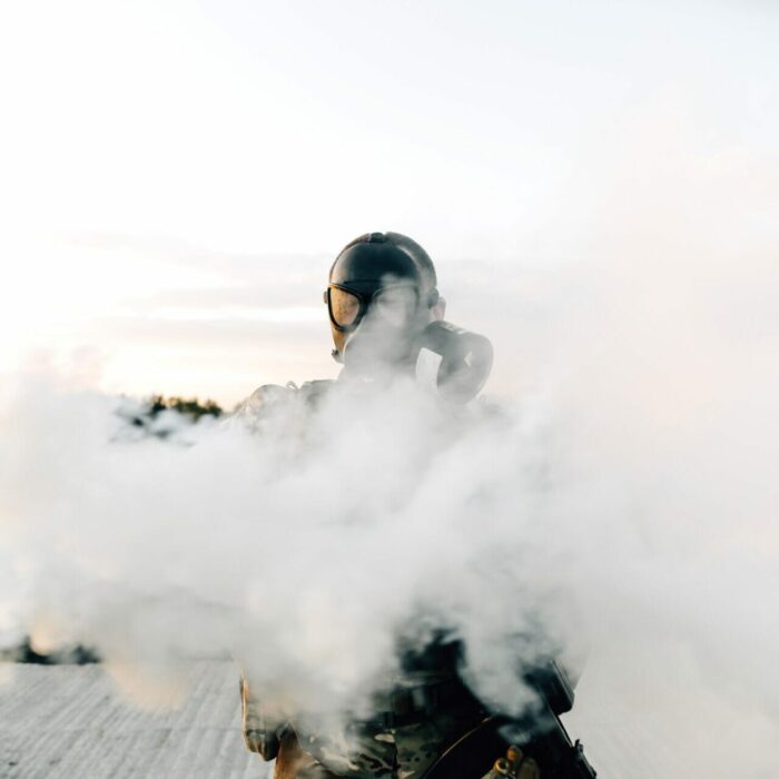 Army soldier in gas mask spraying a gas cylinder in front of him